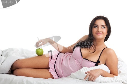 Image of Happy woman in bed with apple