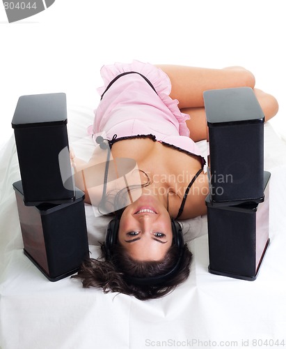 Image of Young woman lay in bed and listen music