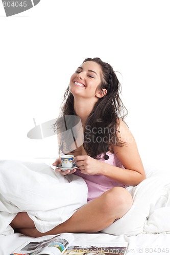 Image of Woman sit in bed laughing and drink coffee