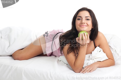 Image of happy young woman in bed with apple