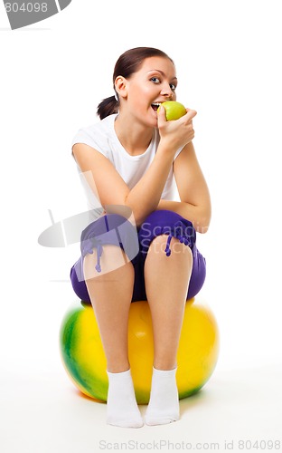 Image of Young woman sit on ball with apple