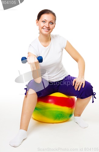 Image of Young woman doing exercises with ball and dummbell