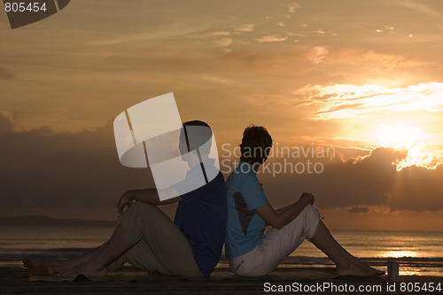 Image of Mature couple sitting in front of sunrise