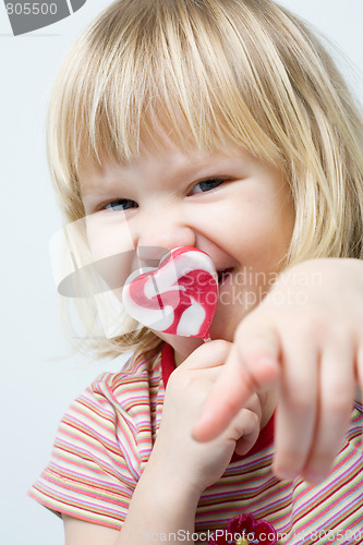 Image of Cute little girl with a heart shape lollipop