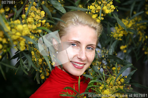 Image of young female face bordered by bright yellow mimosa flowers