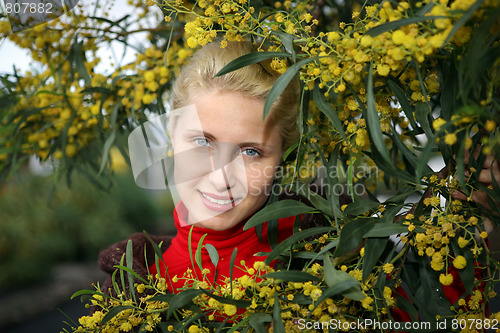 Image of young female face bordered by bright yellow mimosa flowers