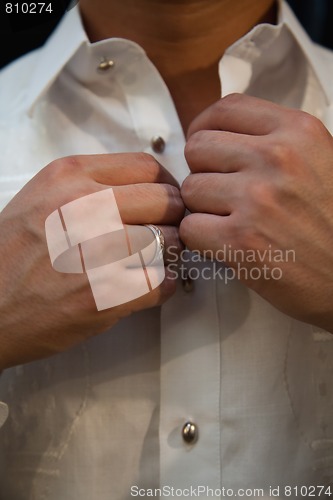 Image of Wedding Groom buttoning shirt