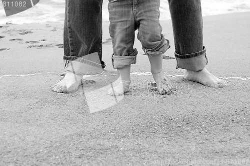 Image of feet of father and child by sea