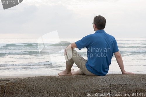 Image of Man sitting on a rock at the sea