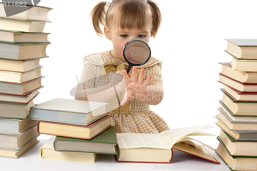 Image of Little girl looking at the book through magnifier, back to school