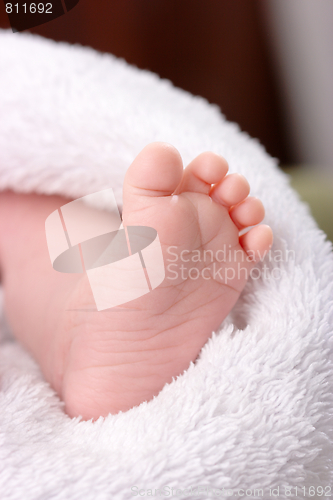 Image of Adorable toddler's foot on white blanket