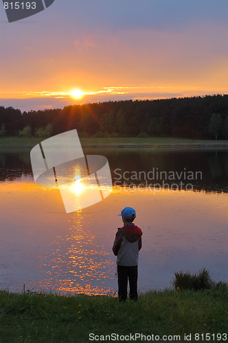 Image of The boy on the shore of lake at sunset