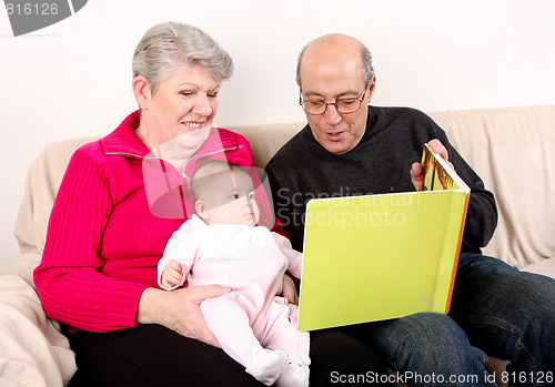 Image of Family reading book to baby