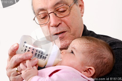Image of Grandpa bottle feeding baby girl