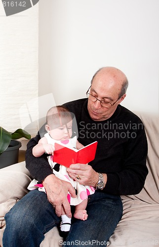 Image of Grandpa reading red book to baby girl
