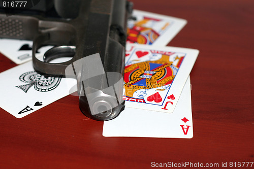 Image of abstract gun and playing cards on table in casino