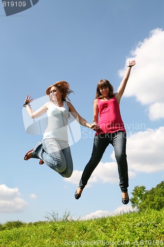 Image of two girls jump under blue sky