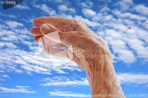 Image of Senior woman's hand over sky