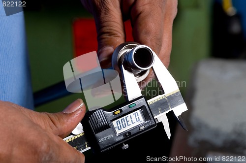 Image of Hands Holding a Tool Measuring a Pipe