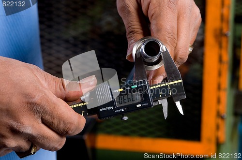 Image of Hands Holding a Tool Measuring a Pipe