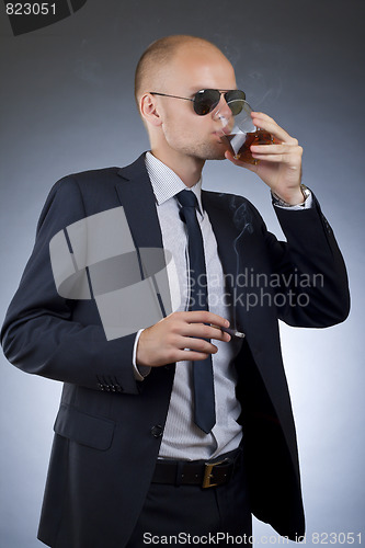 Image of young businessman drinking and smoking