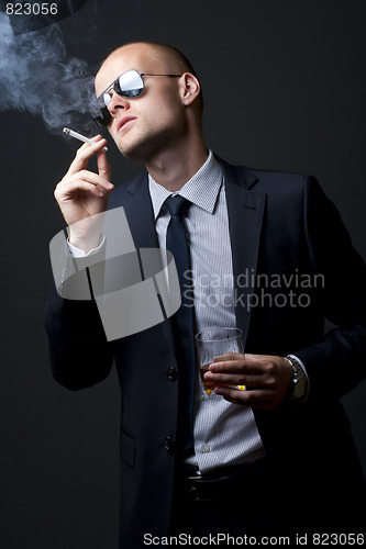 Image of young businessman drinking and smoking