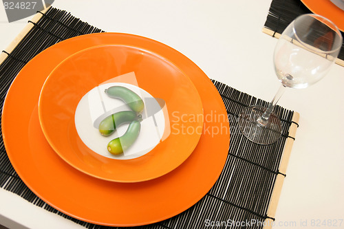 Image of orange plate with artificial cucumber and glass