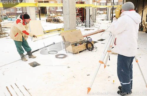 Image of land surveyor workers using theodolite equipment at construction
