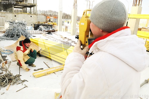 Image of land surveyor workers using theodolite equipment at construction