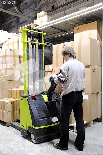 Image of Operator of electric forklift stacker in warehouse