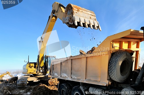 Image of loader excavator loading earth to body of rear-end tipper