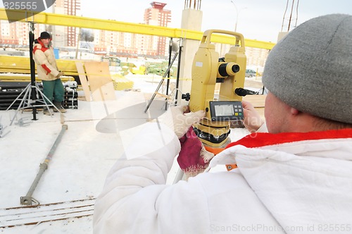 Image of surveyor worker and theodolite at construction site