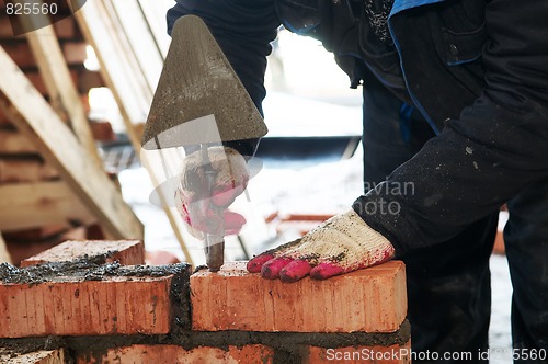 Image of hands of a mason at bricklaying work