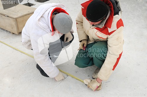 Image of two workers using tape measure