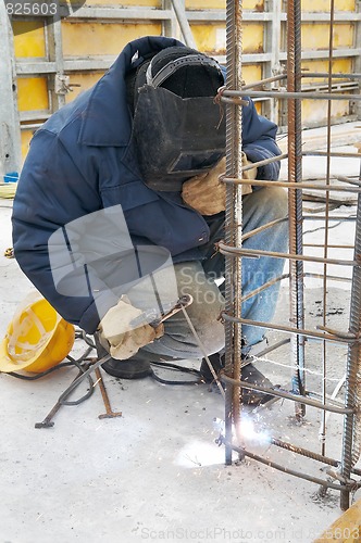 Image of worker welding a metal lattice at construction site