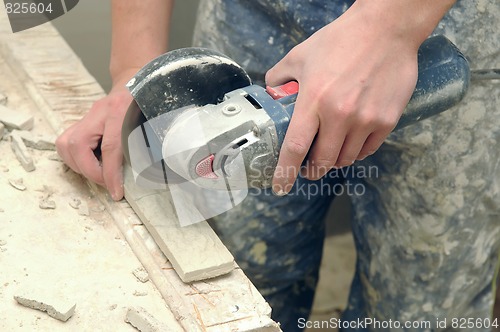 Image of worker hands cutting a tile