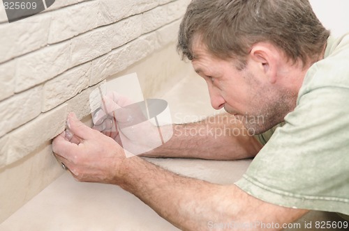 Image of worker tiler at wall decoration work
