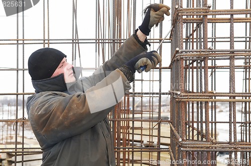 Image of worker making a metal lattice at construction site