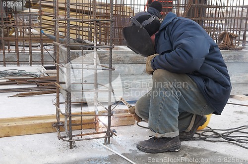 Image of worker welding a metal lattice at construction site