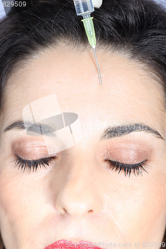 Image of Young woman receives botox injection in her forehead