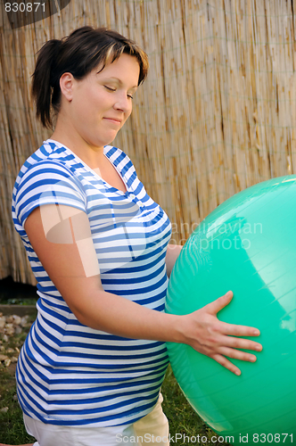 Image of Pregnant young woman exercising with ball