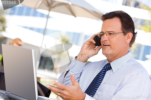 Image of Businessman Talking on Cell Phone Using Laptop