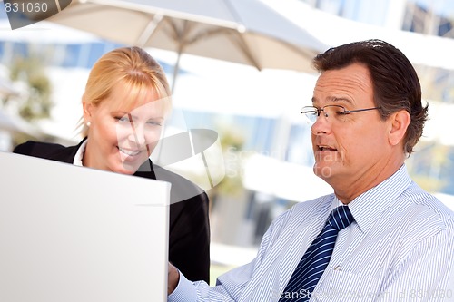 Image of Businessman and Female Colleague Using Loptop Outdoors