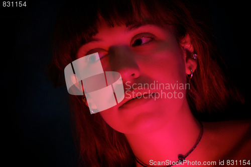 Image of beautiful woman in dark lit by red