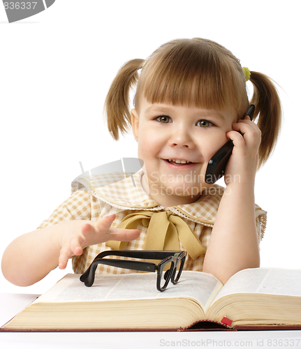Image of Happy little girl with book and a cell phone