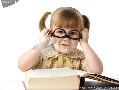 Image of Happy little girl with books wearing black glasses