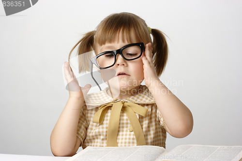 Image of Little girl with books wearing black glasses