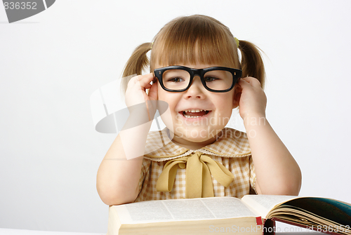 Image of Happy little girl with books wearing black glasses