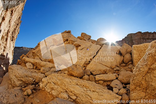 Image of Sun setting behind the yellow sandstone rock in the desert
