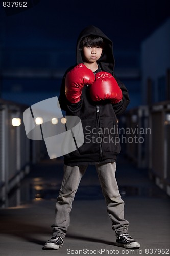 Image of Young intense asian boy wearing boxing gloves